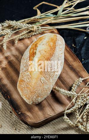 Pain de seigle fraîchement cuit sur levain sans levure et farine de grains entiers, de seigle et de blé. Il repose sur une planche à découper. Banque D'Images