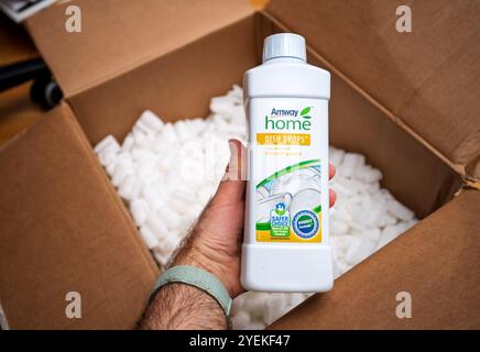 Paris, France - 26 mars 2020 : main tenant une bouteille de liquide vaisselle concentré Amway Home Dish Drops avec étiquettes écologiques, dans une boîte ouverte avec des arachides d'emballage, lors d'un déballage Banque D'Images