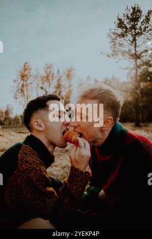 Par une journée ensoleillée d’automne, deux jeunes amis profitent d’un pique-nique à la campagne. Ils partagent un croissant entre eux. Les amis sont feelin Banque D'Images