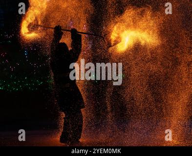 Performance de pot de feu mettant en vedette un artiste manipulant un filet de fer ardent rempli de charbon de bois brûlant, créant une douche à couper le souffle d'étincelles Banque D'Images