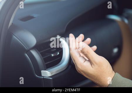 Le propriétaire de la voiture vérifie le système de climatisation en sentant l'air frais de l'évent après que le véhicule a été inondé. Concept d'entretien des véhicules, Banque D'Images