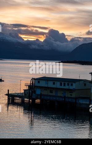 Automne lever le soleil sur la distance des montagnes enneigées et le Vagsfjorden avec un port animé et le port dans une petite ville de Harstad en Norvège, SCA Banque D'Images