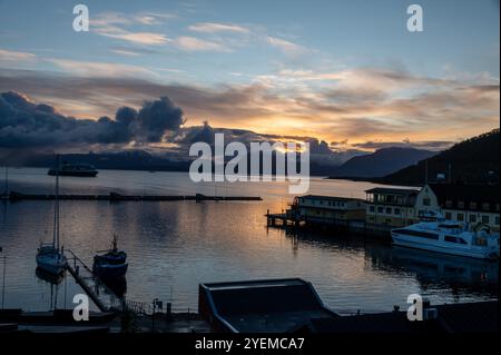 Automne lever le soleil sur la distance des montagnes enneigées et le Vagsfjorden avec un port animé et le port dans une petite ville de Harstad en Norvège, SCA Banque D'Images