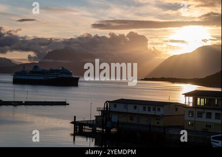 Le bateau de croisière Hurtigruten Trollfjord s'approche du terminal de croisière à Hastad alors que le soleil d'automne se lève sur la distance des montagnes enneigées et Banque D'Images