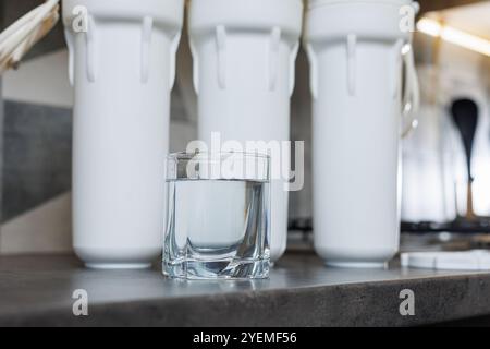 Un verre d'eau filtrée. Système de filtration d'eau avec cartouches remplaçables. Un système dans l'appartement avec trois réservoirs pour nettoyer l'eau du robinet. Banque D'Images