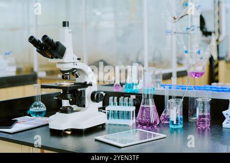 Laboratoire moderne avec microscope entouré de béchers, tubes à essai et autres appareils scientifiques, suggérant une ambiance de recherche scientifique avancée Banque D'Images