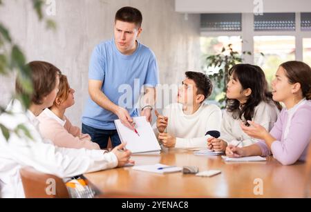 Jeune professeur de sexe masculin expliquant le sujet à un groupe d'étudiants Banque D'Images