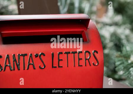 Boîte aux lettres rouge festive pour les lettres du Père Noël entourées de festivités. Banque D'Images