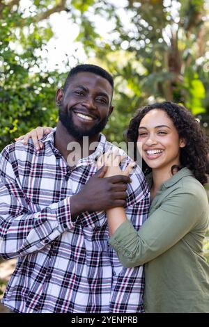 Couple multiracial souriant embrassant à l'extérieur, profitant d'un moment joyeux ensemble dans la nature. Romance, bonheur, amour, relation, étreinte Banque D'Images