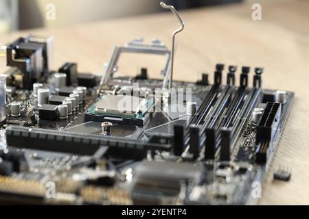 Carte mère avec puce informatique moderne et d'autres composants sur table en bois, gros plan Banque D'Images