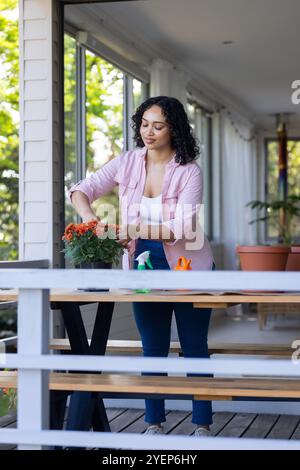 Femme s'occupant des plantes sur le porche, profitant du jardinage dans l'espace extérieur ensoleillé. horticulture, soleil, week-end, détente Banque D'Images