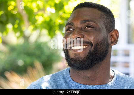 Homme afro-américain souriant profitant du soleil extérieur, se sentant heureux, copiez l'espace. bonheur, détente, plein air, loisirs, bien-être, tranquillité Banque D'Images