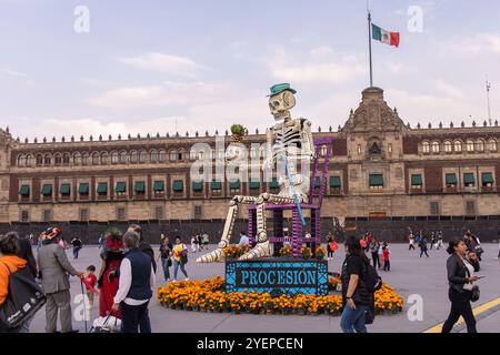 Une sculpture de squelette géante assise dans une chaise décorée avec des soucis à Mexico Zócalo pour le jour des morts. Traduction : procession Banque D'Images