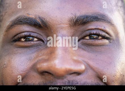 Gros plan des yeux et du sourire de l'homme, exprimant la chaleur et le bonheur, à la maison. masculin, expression, portrait, émotions, visage, joyeux Banque D'Images