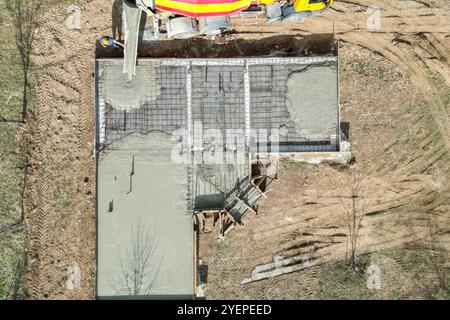 Chantier de construction, vue aérienne, ouvrier constructeur coulant du béton à partir d'une bétonnière pour une dalle d'une nouvelle maison Banque D'Images