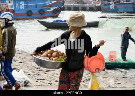 12/02/2017 - Da Nang, Vietnam : un vendeur local au marché de pêche animé de Da Nang propose des fruits frais, avec des bateaux animés et des commerçants dans l'arrière-pays Banque D'Images