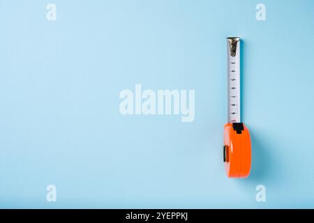 Mètre ruban rétractable orange sur fond bleu Banque D'Images