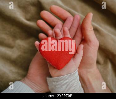 Macaron en forme de coeur dans les mains de l'enfant, maman et papa Banque D'Images