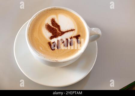 Tasse de café cappuccino avec logo WWT en forme de cygne en vol au WWT Welney Wetland Centre, Norfolk, Angleterre, Royaume-Uni Banque D'Images