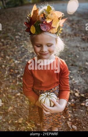 Portrait d'automne fantaisiste de fille dans la couronne de feuille tenant la citrouille Banque D'Images