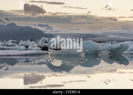 Icebergs reflétés dans l'eau calme sur fond de montagne, nuages, lagune glaciaire de Joekulsarlon ou Joekulsarlon, Sud de l'Islande, Islande, Europe Banque D'Images