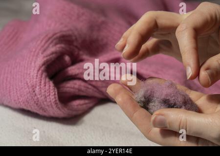 Femme utilisant le rasoir anti-boulochage à la maison. Dispositif pour raser des vêtements. Rasoir à tissu anti-peluche. Détartrant de peluches pour chandail portable électrique Banque D'Images