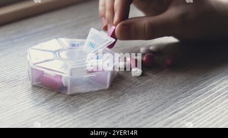Femme trier les pilules Organiseur des injections hebdomadaires gros plan de la boîte de pilules médicales avec des doses de comprimés pour la journée prendre des médicaments avec des médicaments blancs roses et capsule Banque D'Images