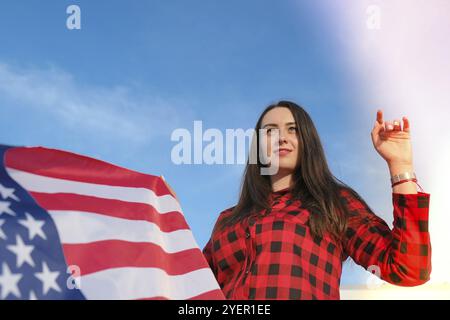 Jeune femme brunette millénaire tenant le drapeau national des États-Unis. Drapeau américain. Touriste ou patriotisme. Immigrant dans le pays libre. 4 juillet I Banque D'Images