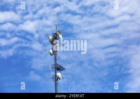 Une vue en angle bas des nuages dispersés derrière une tour cellulaire. Technologie et équipement électroniques de télécommunications. Amplificateur de signal pour téléphone mobile Banque D'Images