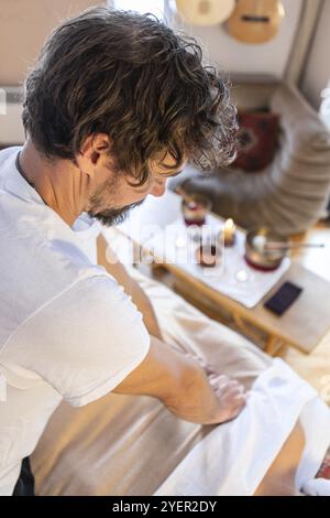 Un masseur professionnel offrant un massage de traitement pour une jeune femme posée sur un lit de massage. Massothérapie. Vue de dessus. Image verticale Banque D'Images
