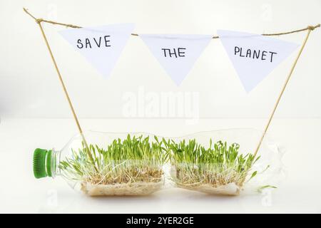 SAUVER LA PLANÈTE jeunes plantes vertes dans une bouteille en plastique. Écologie et conversation environnementale. Concept du jour de la Terre. Pollution mondiale de la planète. Sél Banque D'Images