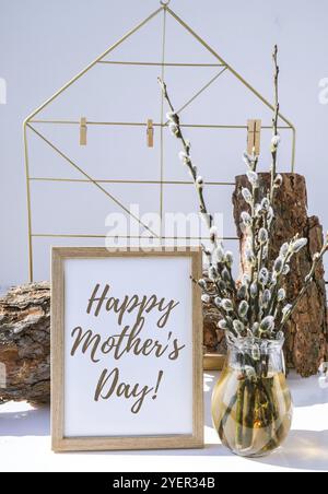 Happy Mothers Day lettering maquette intérieur cadre photo avec branche de saule dans vase en verre.Brunch de la chatsysaule en pleine floraison au début du printemps.Art Banque D'Images