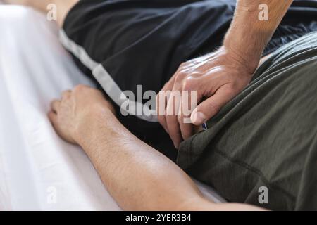 Thérapeute professionnel massant un homme musculaire couché. Mains de masseur donnant un massage de traitement à son client. Massage corporel Banque D'Images