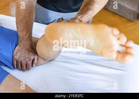 Masseur masculin masseur massant les pieds. Massage thérapeutique du corps. Masseuse professionnelle offrant un massage des jambes à un sportif Banque D'Images