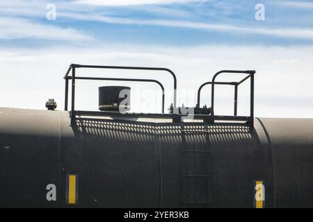 Gros plan du dôme et de la couverture du passage d'homme d'un wagon-citerne peint en noir. Train de marchandises vintage canadien ou train de marchandises se déplaçant à la campagne Banque D'Images