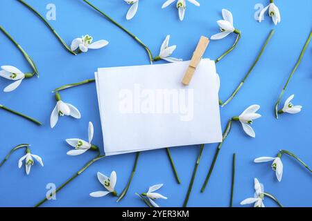 Composition de pose à plat avec fleurs en forme de goutte d'eau sur fond couleur, feuille vierge d'espace de copie d'étiquette de papier vide pour le texte. Carte de vœux factice pour les fêtes. Haut Banque D'Images