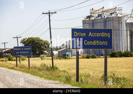 Français, Anglais de la signalisation routière, l'information en fonction des conditions d'entraînement. Pays rural canadien de la route, les silos à grains dans l'arrière-plan, Ontario Canada Banque D'Images