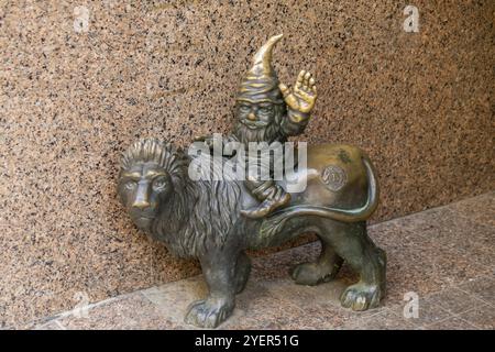 Nain chevauchant un chapeau de lion de couchage assis sur un lion et saluant. Petites figures en bronze de gnomes dans les rues de Wroclaw. Europe miniature bronze Banque D'Images