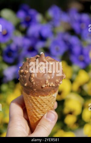 Main féminine tenant une délicieuse glace au chocolat à la vanille américaine. Glace savoureuse maison Gelato dans le cône de gaufres. ic sans gluten, végétalien, sans lait Banque D'Images