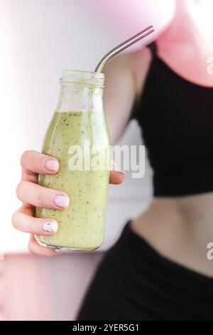 Jeune femme blonde millénelle boit du smoothie végétalien Detox. Femme faisant des exercices de yoga à la maison. Alimentation propre, perte de poids, alimentation saine c Banque D'Images