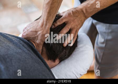 Un jeune homme sur le massage sportif de traitement de bien-être. Un massothérapeute sportif masculin faisant un massage de la tête et du cou. Un sportif qui profite d'un massage Banque D'Images