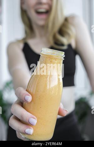 Jeune femme blonde millénelle boit du smoothie végétalien Detox. Femme faisant des exercices de yoga à la maison. Alimentation propre, perte de poids, alimentation saine c Banque D'Images