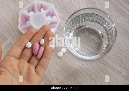 Femme trier les pilules Organiseur des injections hebdomadaires gros plan de la boîte de pilules médicales avec des doses de comprimés pour la journée prendre des médicaments avec des médicaments blancs roses et capsule Banque D'Images