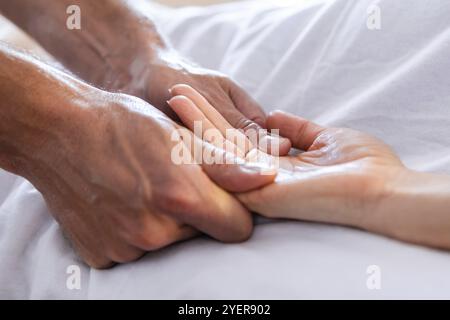 Vue rapprochée du masseur donnant un massage relaxant des mains à un client. Massage des mains à une femme dans un environnement confortable à la maison. Massage et soins du corps Banque D'Images