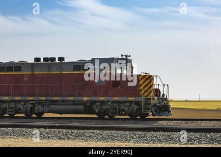 Locomotive d'époque d'un train de marchandises d'époque des chemins de fer nationaux du Canada, rouge avec des bandes jaunes. Se déplacer vers la droite dans la campagne Banque D'Images