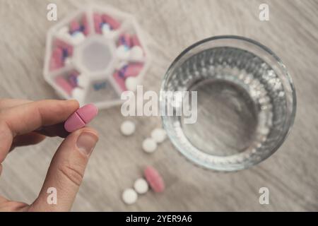 Femme trier les pilules Organiseur des injections hebdomadaires gros plan de la boîte de pilules médicales avec des doses de comprimés pour la journée prendre des médicaments avec des médicaments blancs roses et capsule Banque D'Images