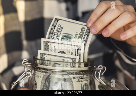 Billet de banque en dollar permettant d'économiser de l'argent dans un pot en verre. Femme méconnaissable consommation modérée et économie collectant de l'argent. Conseils. Affaires, finances, épargne, ba Banque D'Images