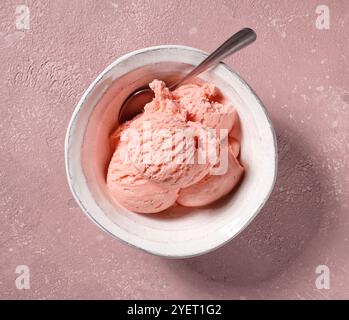 gros plan du bol de crème glacée à la fraise rose sur la table de couleur rose, vue de dessus Banque D'Images