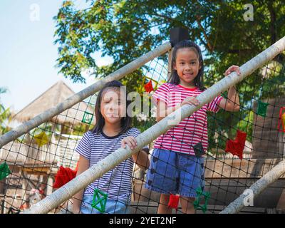 Les enfants jouent à l'extérieur sur une aire de jeux avec toboggans modernes, ponts en filet de corde, balançoires d'escalade, grimpeurs en été. Banque D'Images