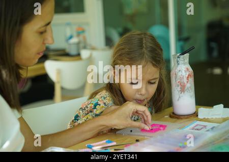 Professeur dans l'atelier a techno deux filles comment assembler une mosaïque thermo Banque D'Images